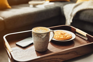 Mug of coffee, pastry and iPhone on a tray